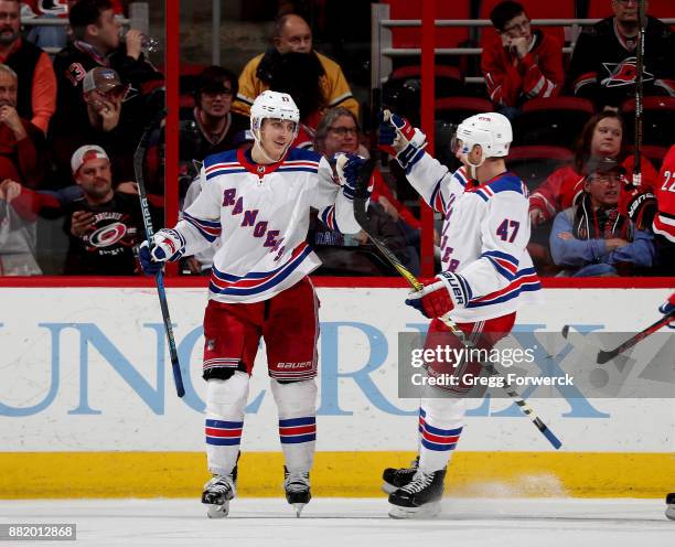 Jesper Fast of the New York Rangers scores a goal and celebrates with teammate Steven Kampfer during an NHL game against the Carolina Hurricanes on...