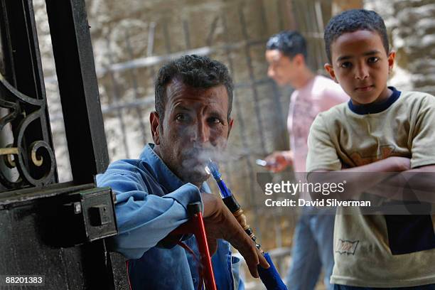 An Egyptian man smokes a water-pipe as he and his son watch US President Barack Obama's key Middle East speech on TV in a coffee shop in the Islamic...