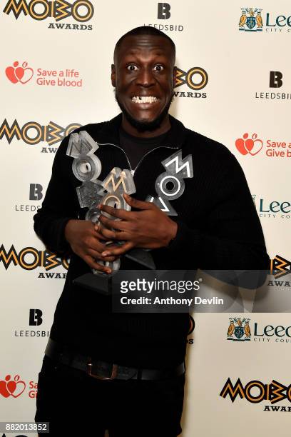 Stormzy poses in the winners room with the awards for Best Male, Best Grime and Best Album at the MOBO Awards at First Direct Arena Leeds on November...