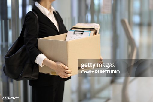 Businesswoman leaving office with box of personal items Businesswoman leaving office with box of personal items
