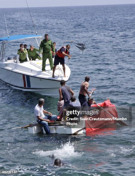 Cuban security officer throws an anchor toward a raft after seven men failed in an attempt to leave the island at the Malecon waterfront on June 4,...