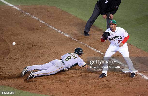 Center fielder Trent Oeltjen of Australia dives back to first base while trying to avoid the tag by first baseman Adrian Gonzalez of Mexico during...