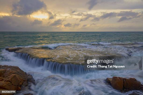 sea waterfall over rock at dawn - duden stock-fotos und bilder