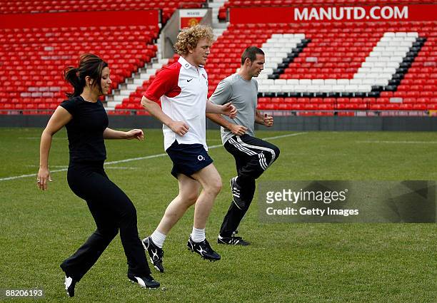 Chris Foy of the Daily Mail and Gail Davis of Sky Sports News warm up with England's Sam Vesty during a kicking clinic for media at Old Trafford on...
