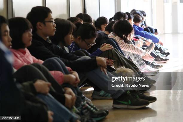 Sixth graders at an elementary school in Morioka in northeastern Japan's Iwate Prefecture sit in a corridor during an emergency drill on Nov. 29...