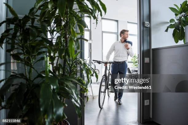 smiling businessman with bicycle in the office - sport office foto e immagini stock