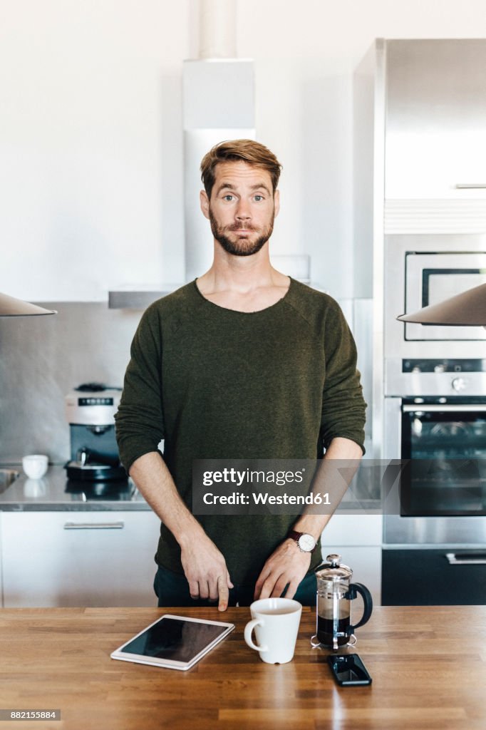 Portrait of man standing in kitchen raising his eyebrows