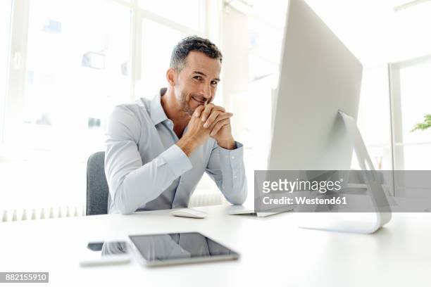 portrait of smiling businessman at desk in office - confident desk man text space stock pictures, royalty-free photos & images