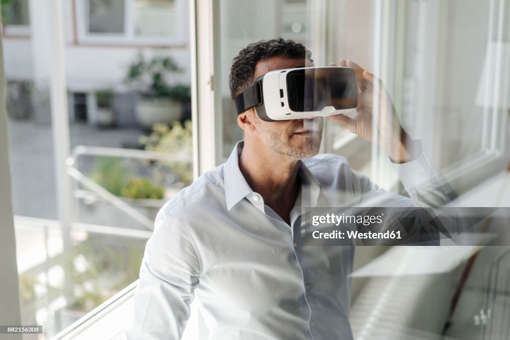 Businessman at the window wearing VR glasses