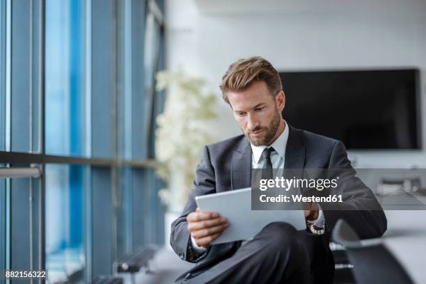 businessman sitting in conference room using tablet - vogues forces of fashion conference stockfoto's en -beelden