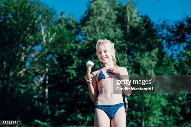 portrait of smiling blond girl with ice cream cone wearing bikini - eis baden stock-fotos und bilder