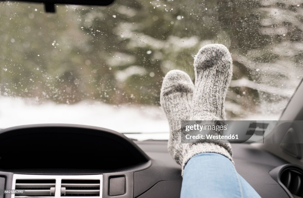 Woman sitting in car with feet up on dashboard