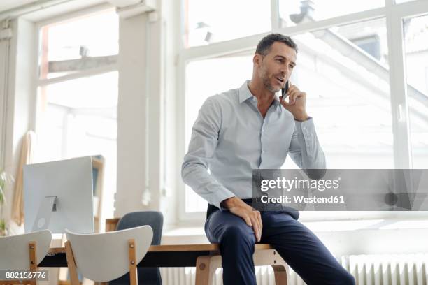 businessman in office talking on cell phone - geschäftsmann im büro mobiltelefon stock-fotos und bilder