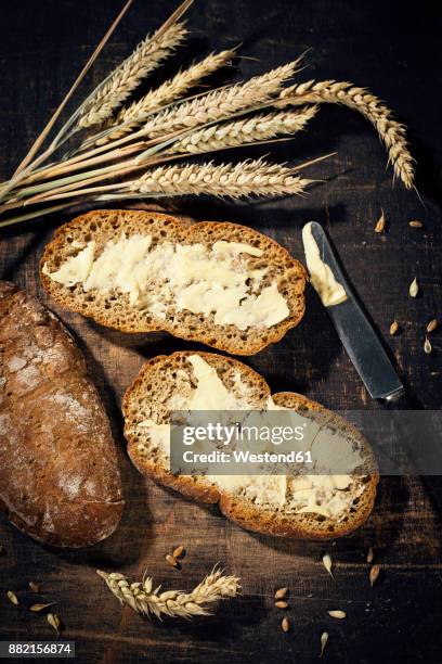 buttered bread and ear of wheat on dark wood - untar de mantequilla fotografías e imágenes de stock