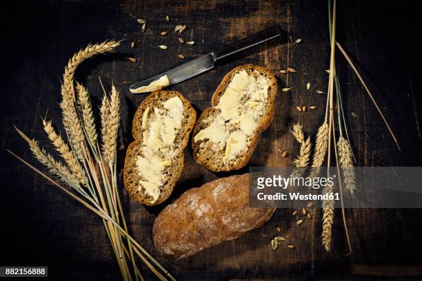 buttered bread and ear of wheat on dark wood - wood grain 個照片及圖片檔
