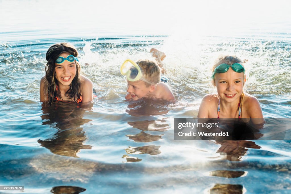 Three smiling friends splashing with water at lakeshore