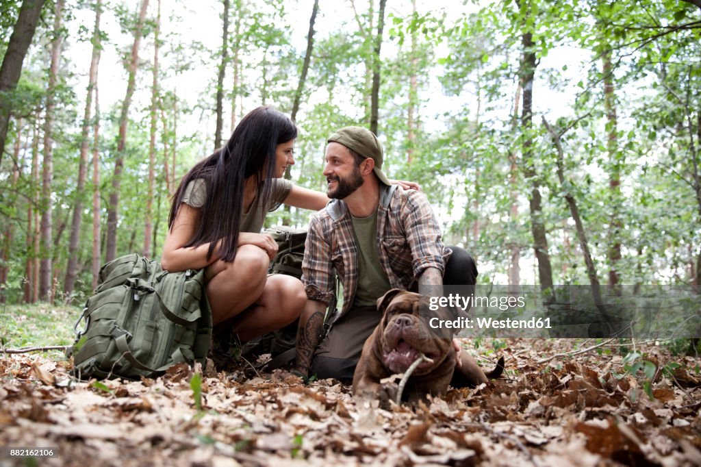 Couple with backpack and dog in forest