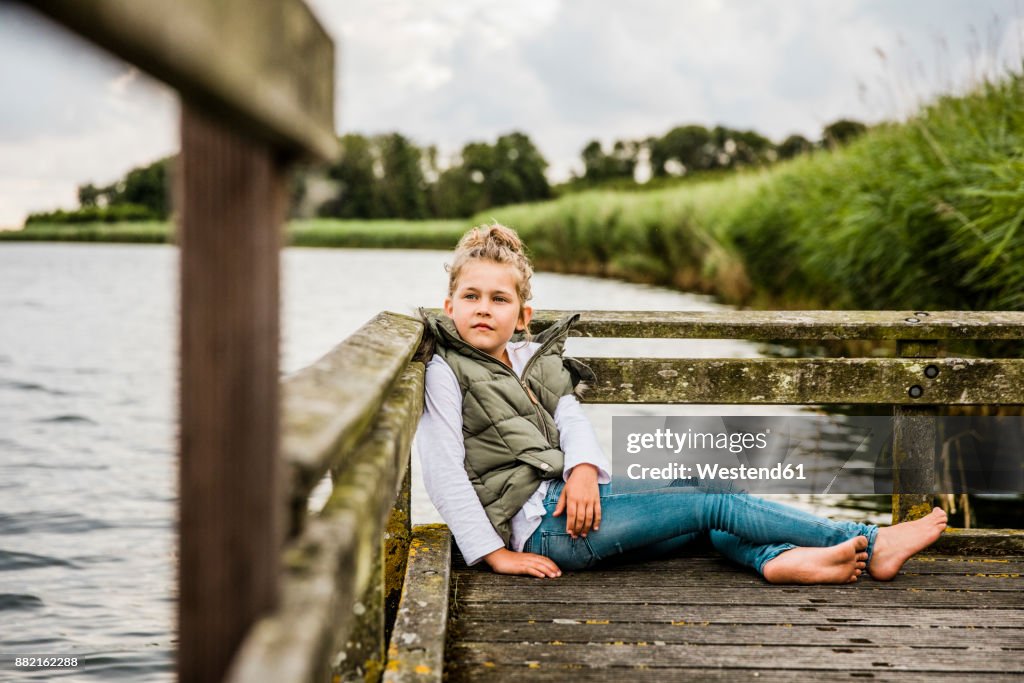 Girl sitting on jetty at a lake