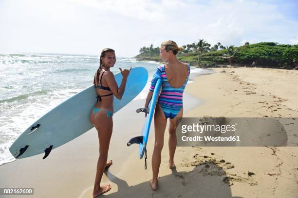two women running on the beach with surfboards - palm beach florida stock pictures, royalty-free photos & images