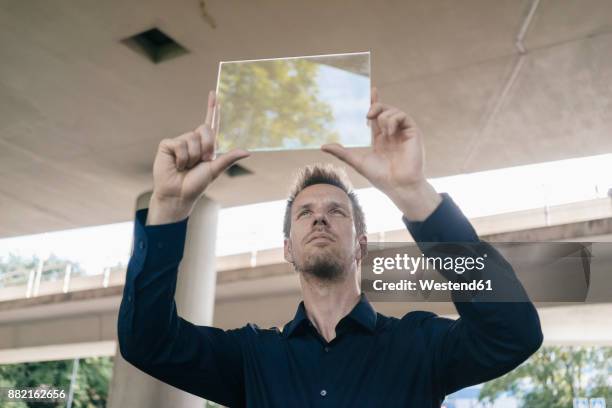 businessman holding up portable glass device - mensch transparent stock-fotos und bilder