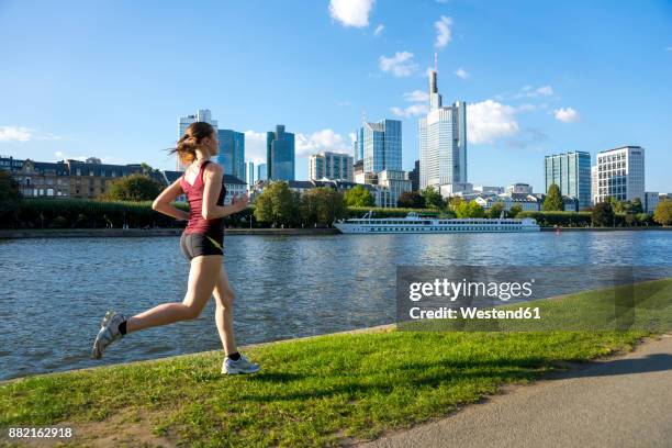 germany, frankfurt, young woman running at riverside - main stockfoto's en -beelden