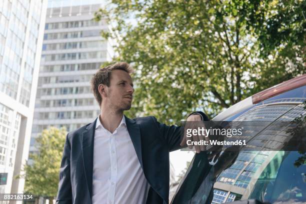 businessman standing next to car with reflection of an office tower - leaning tree stock pictures, royalty-free photos & images