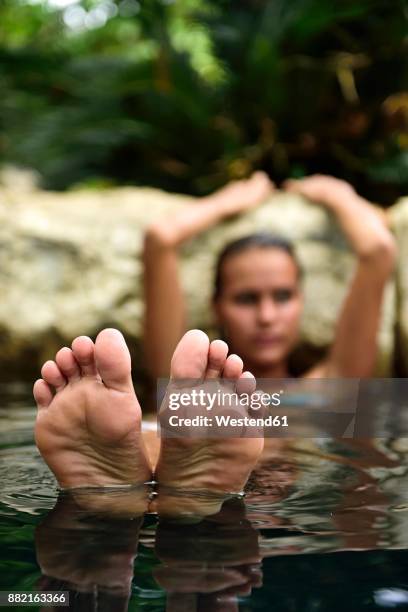 feet of young woman relaxing in natural pool - female soles stock-fotos und bilder