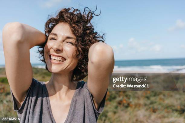 portrait of happy woman at the coast - tossing hair facing camera woman outdoors stock pictures, royalty-free photos & images