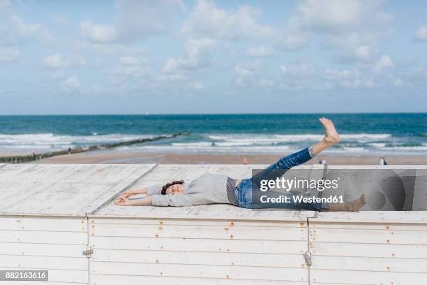 woman lying on wooden box on the beach - auf dem rücken liegen stock-fotos und bilder