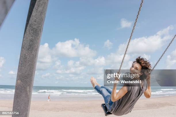 happy woman on a swing on the beach - balançoire photos et images de collection