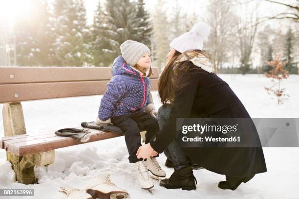 mother helping daughter to put on her ice skates - family ice skate stock pictures, royalty-free photos & images