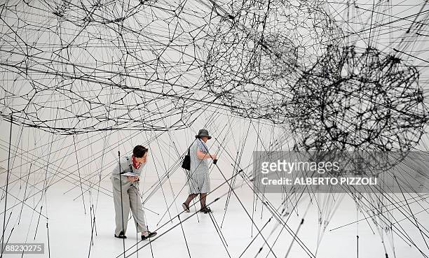 Visitors look at "Galaxies forming along filament like droplets along the stands of a spider's web" by Argentinian artist Tomas Saraceno at the...