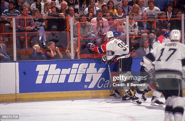 Canadian ice hockey player Wayne Gretzky of the Los Angeles Kings checks an opponant into the boards which causes American actress Goldie Hawn and...