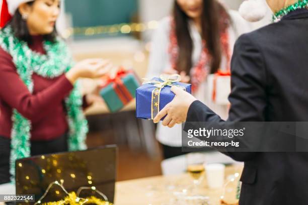uitwisselen van kerstcadeaus - christmas party office stockfoto's en -beelden