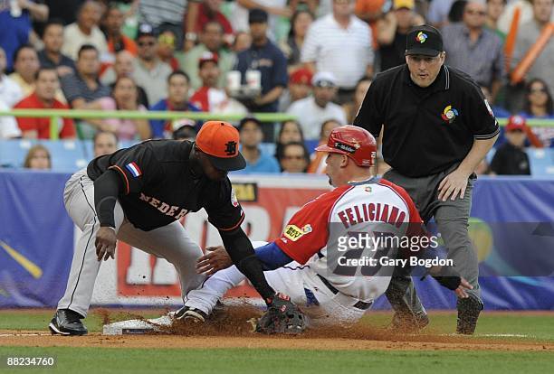 Puerto Rico's Jesus Feliciano is safe at third base as The Netherlands Yurendell de Caster misses the tag during the Pool D Game 6, of the first...