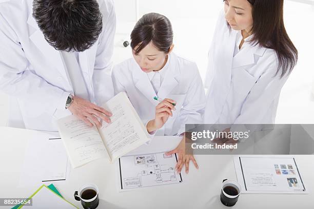 three scientists working at table, high anlge view - scientist standing next to table stock pictures, royalty-free photos & images