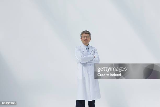 male doctor crossing arms - laboratoriumjas stockfoto's en -beelden