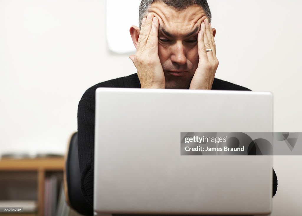 Man making faces from behind laptop