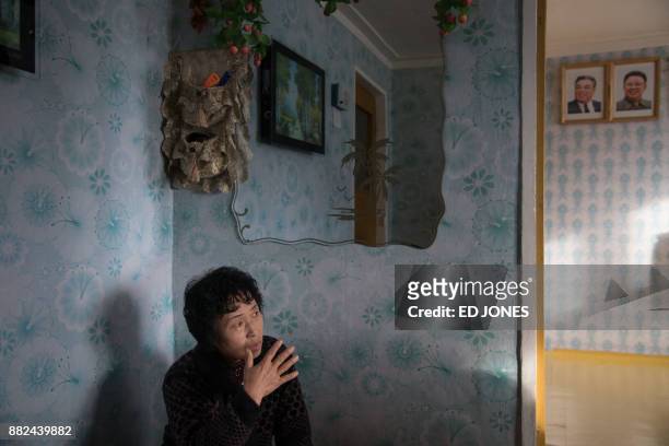 In a photo taken on November 21 Ra In-Hae sits in her new home after her old house was damaged by flooding, before the portraits of late North Korean...