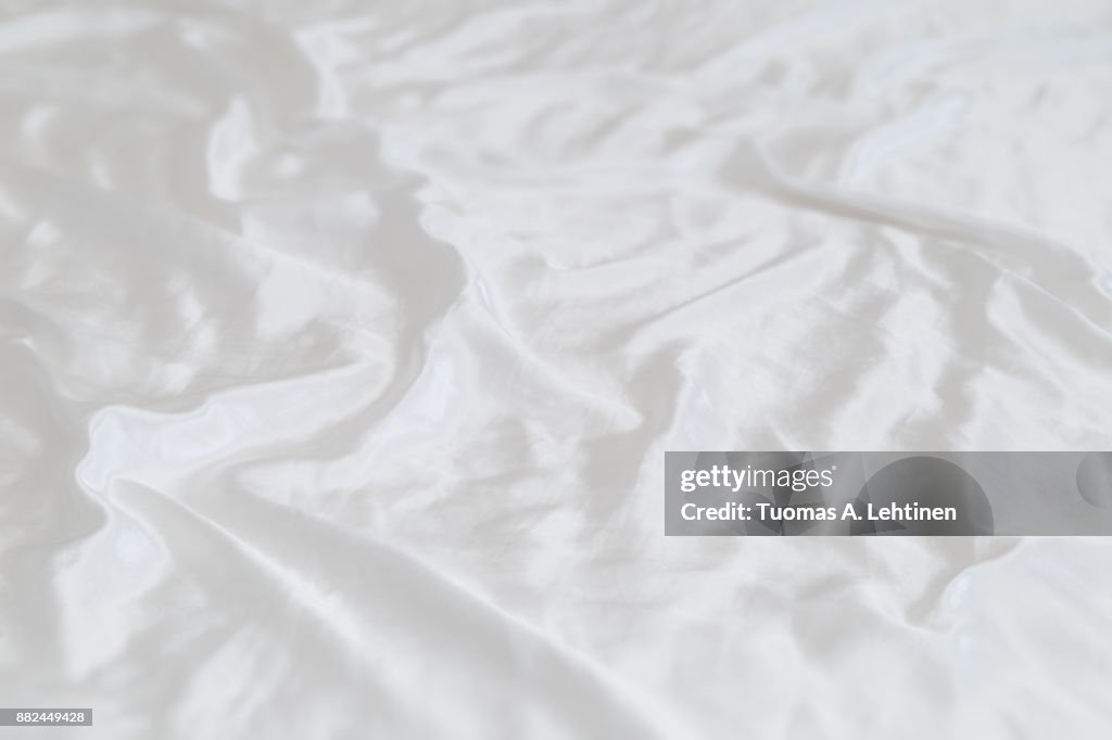 White shiny and soft polyester satin sheet background. Shallow depth of field.