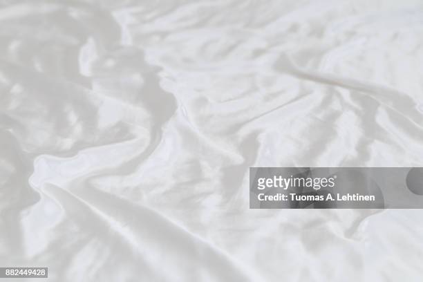 white shiny and soft polyester satin sheet background. shallow depth of field. - white silk stock pictures, royalty-free photos & images