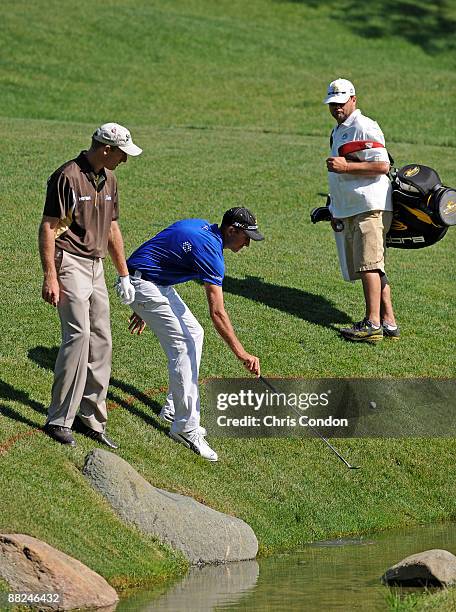Geoff Ogilvy of Australia retrieves his ball from a water hazard on as Jim Furyk looks on during the second round of the Memorial Tournament at...
