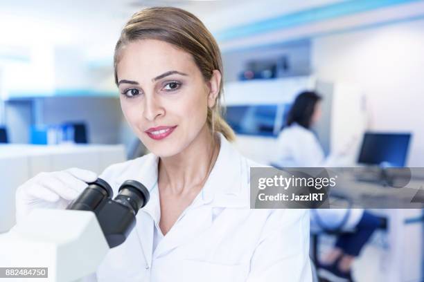 frau arbeitet in einem labor mikroskop - arzneimittelherstellung stock-fotos und bilder