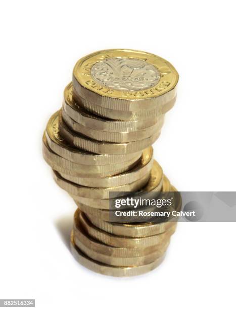precariously stacked one pound coins on white. - pièce de monnaie britannique photos et images de collection