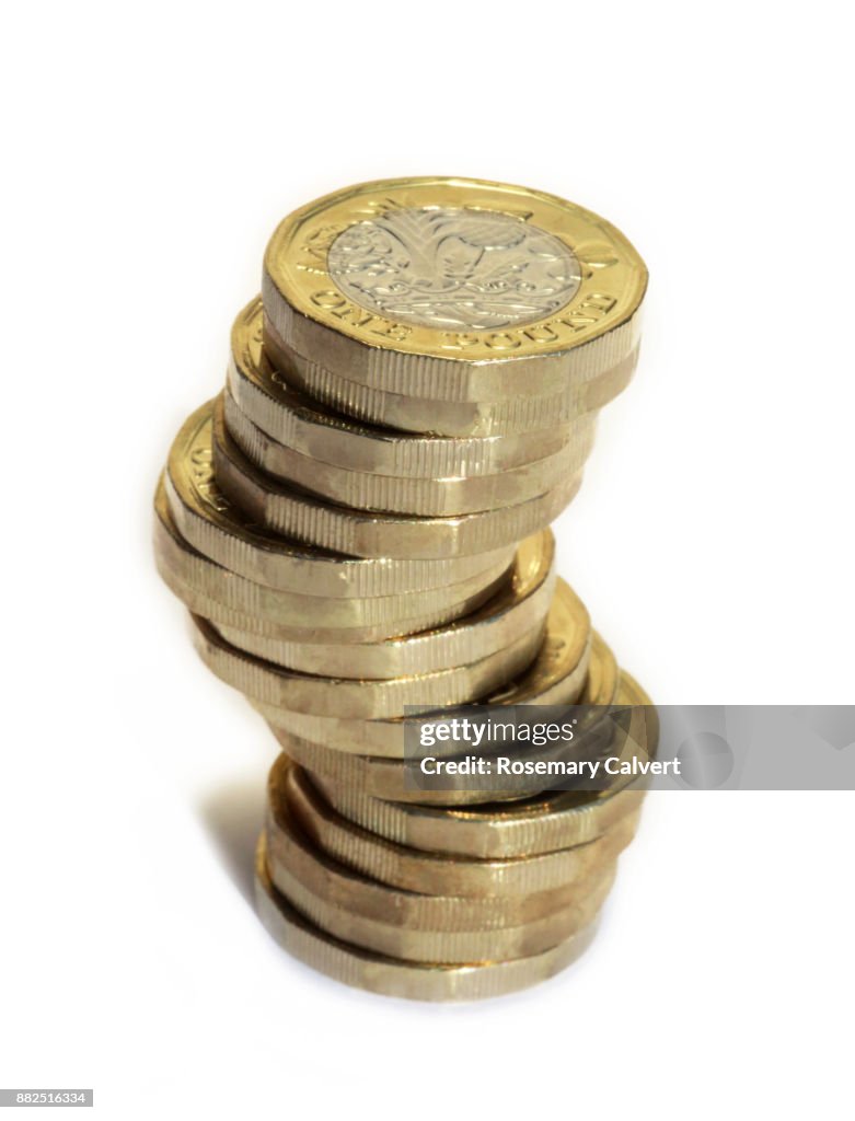 Precariously stacked one pound coins on white.