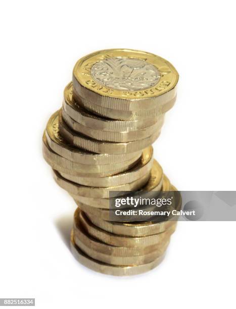 precariously stacked one pound coins on white. - british pound sterling stock pictures, royalty-free photos & images