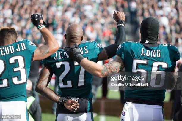Rodney McLeod and Malcolm Jenkins of the Philadelphia Eagles raise their fists as teammate Chris Long stands alongside them during the national...