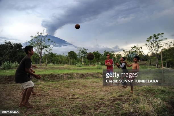 Children play with a ball before Mount Agung in Karangasem on Indonesia's resort island of Bali on November 30, 2017. Thousands of foreign tourists...
