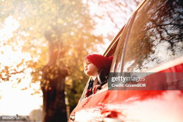 de kleine jongen kijkt uit het raam van de auto - sun flare on glass stockfoto's en -beelden