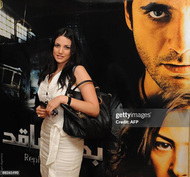 Tunisian actress Dorra Zarrouk poses in front of a poster advertising the premiere of the Egyptian movie "Badal Faqed" at a movie theatre in Cairo...
